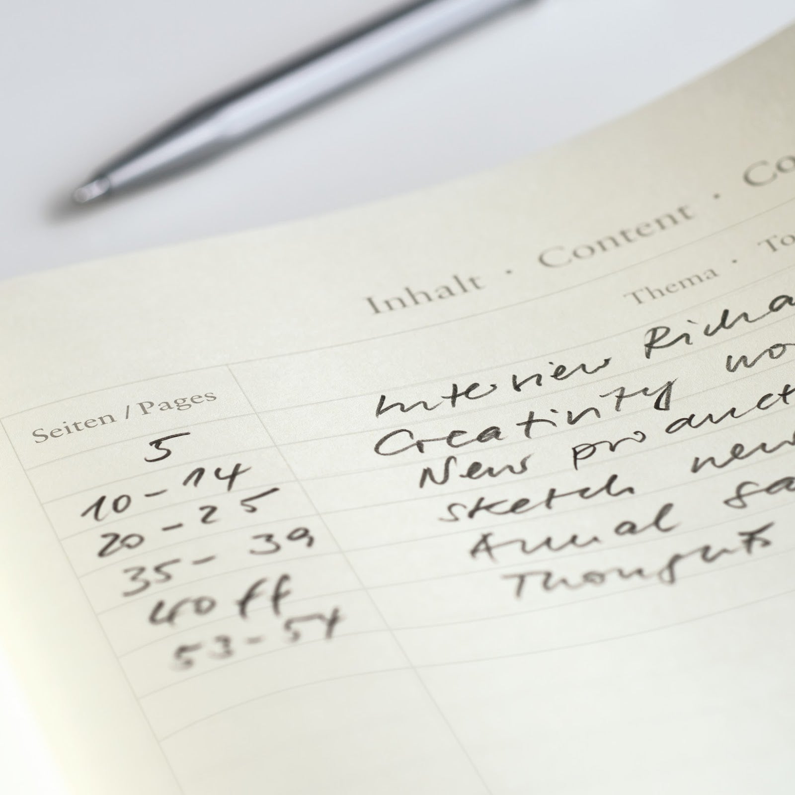 Notebook page with handwritten text and a pen on a white surface