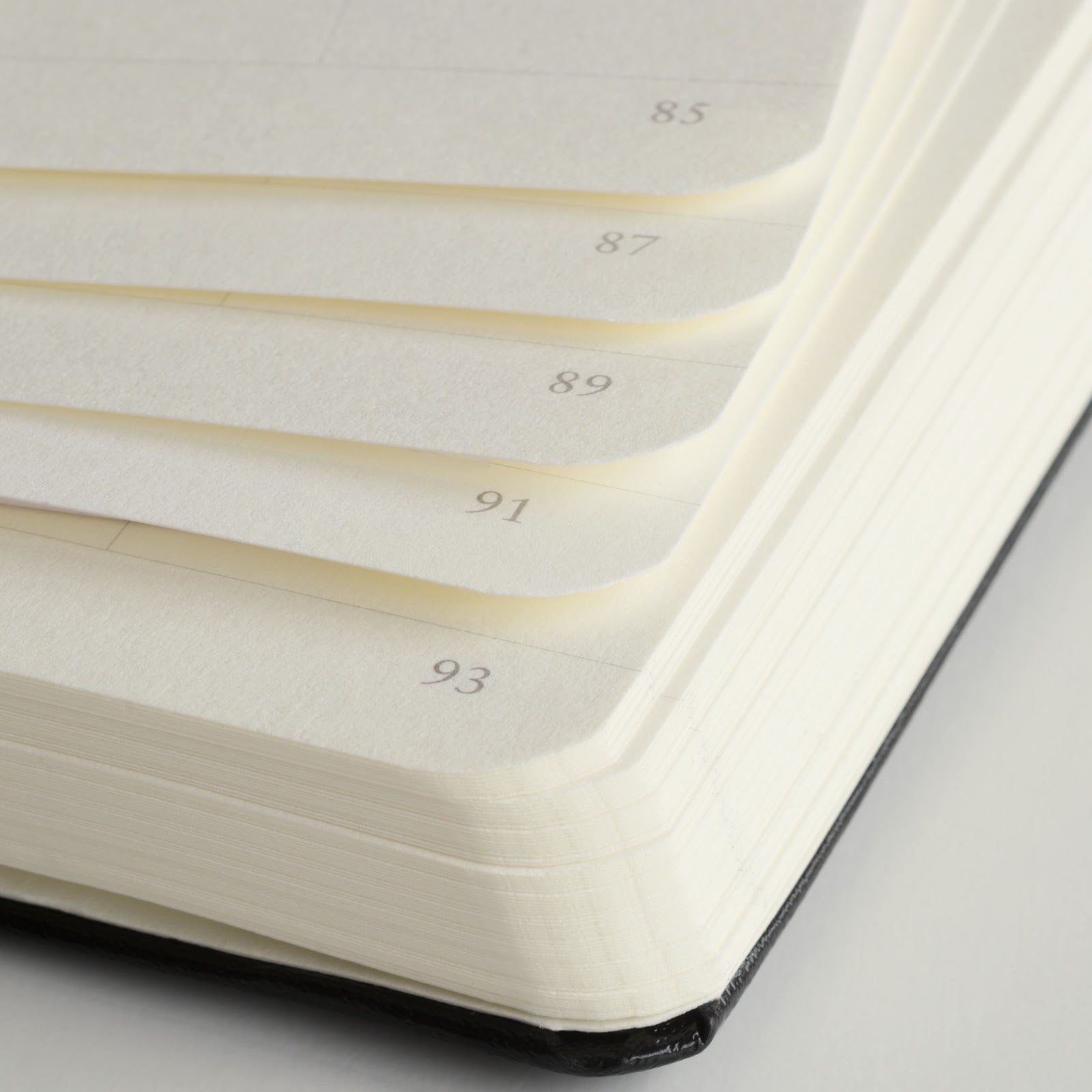 Close-up of a notebook with pages numbered on a gray background