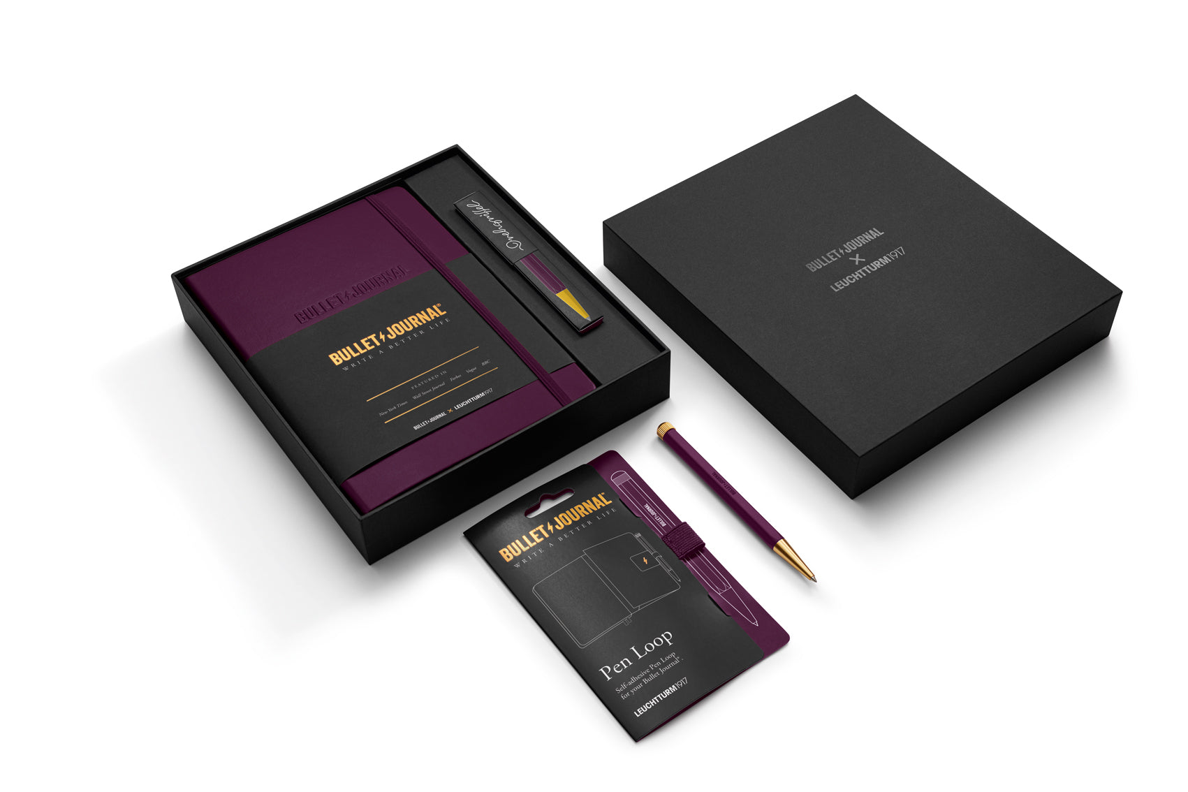A premium gift set from Bullet Journal Club, featuring a black notebook with a deep purple cover, a matching purple and gold pen, a black branded box, a card, and a pen loop, arranged on a clean white background.