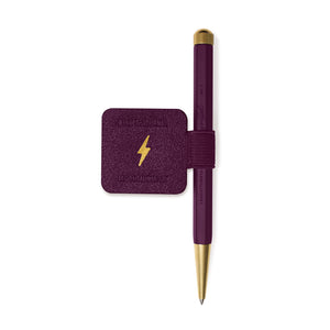 A purple and gold Magic: The Gathering pen with a matching purple textured holder featuring a gold lightning bolt logo, shown on a plain white background.