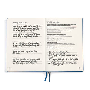 Open notebook with handwritten weekly reflections and planning on cream pages.