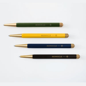 Four pens in green, yellow, blue, and black with 'Monocle' branding on a white background.