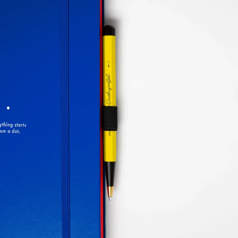 Yellow pen with black cap leaning against a blue notebook on a white background