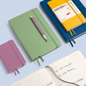 Colorful notebooks and a pen on a light blue background