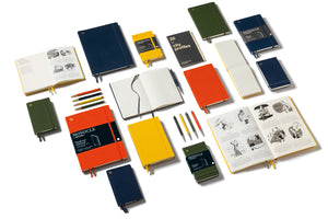 An assortment of Minocci notebooks, journals, and sketchbooks in various colors, including navy, green, yellow, orange, and white, arranged on a clean white background. Several items are open to show the interior pages, and some feature the Minocci brand name visible on the covers.