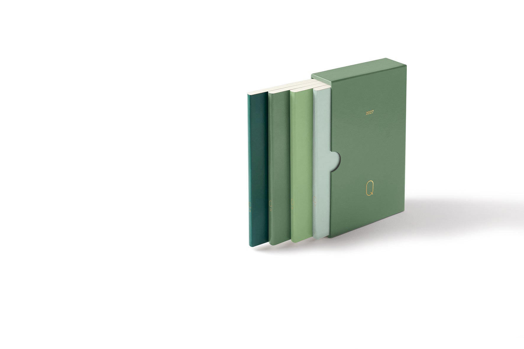 A slim green notebook or journal with a matching pocket clip cover, shown standing upright with three other notebooks fanned out behind it on a clean white background.