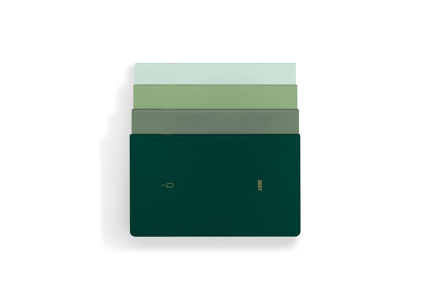 A stack of four slim rectangular notebooks or journals in shades of green, with the top two in pale green and the bottom two in darker green, including a dark forest green cover with gold foil text and logo, set against a plain white background.