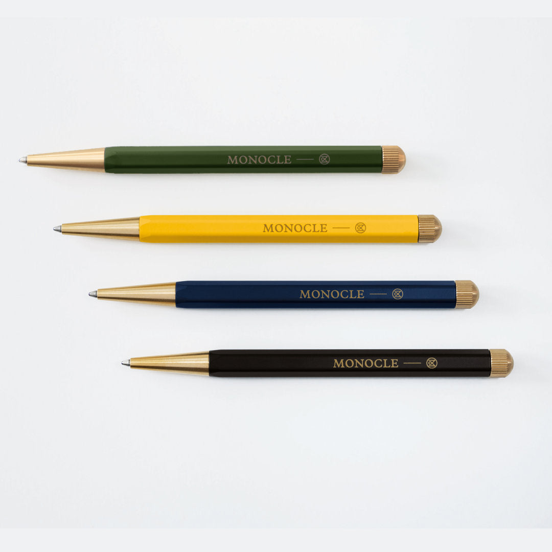 Four pens in green, yellow, blue, and black with 'Monocle' branding on a white background.