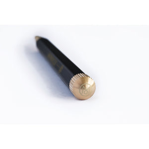 A black cosmetic pencil with a textured gold cap and gold lettering, shown diagonally on a plain white background.