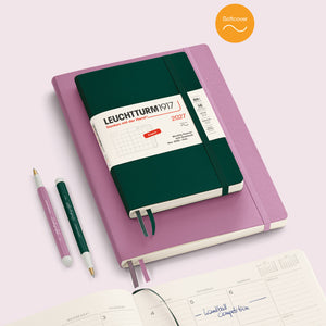 Leuchtturm1917 notebook with pink cover and green interior on a light pink background