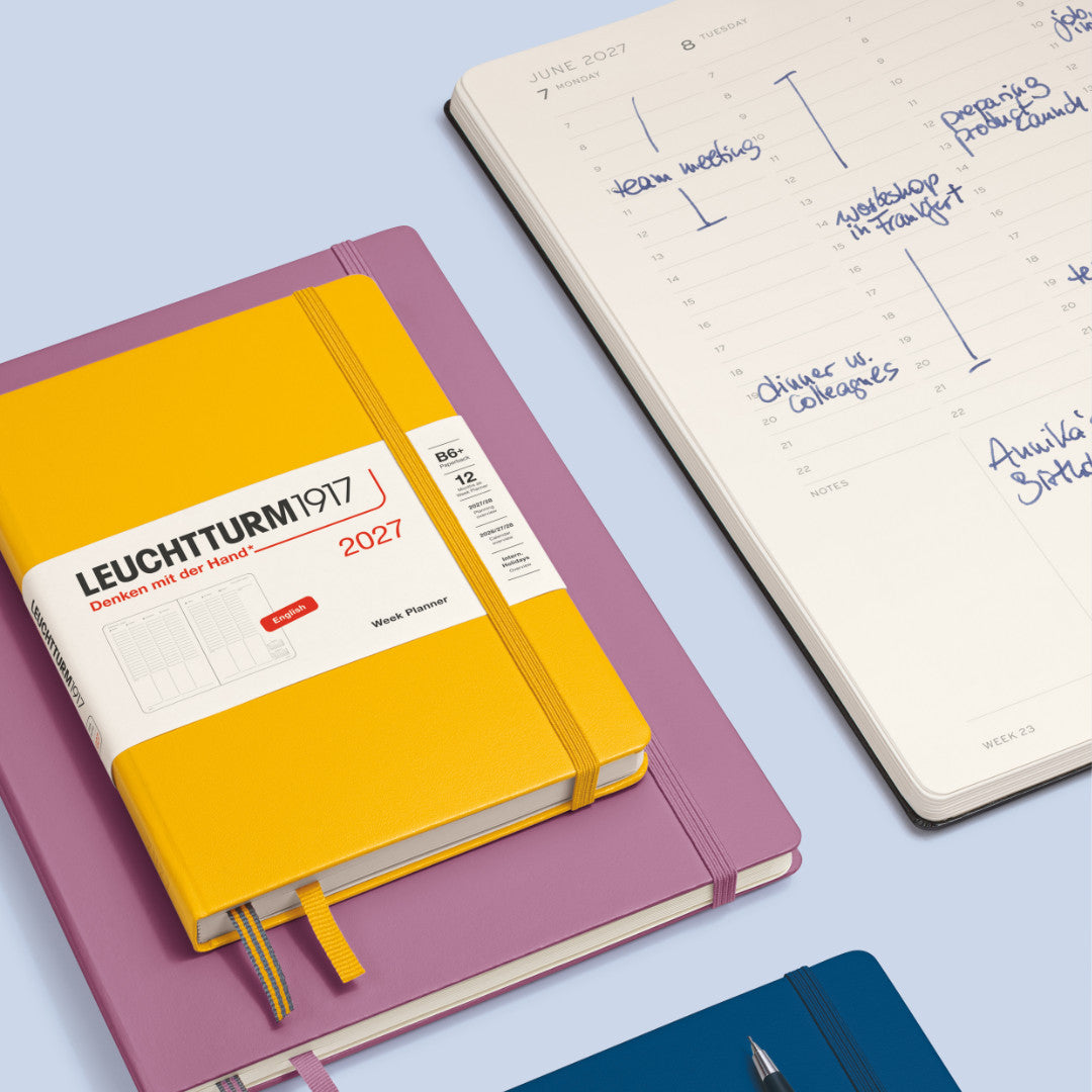 Leuchtturm1917 planner with a pink cover and yellow spine on a light blue background