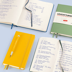 Open notebooks with writing on a light blue background, featuring Leuchtturm1917 brand.